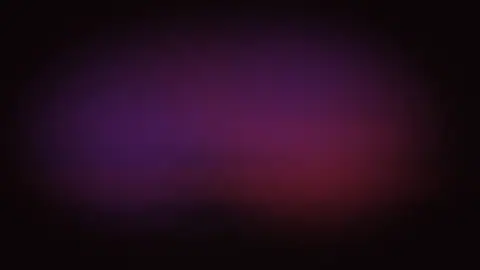 Keyframe from a stage performance clip lit in deep red and violet